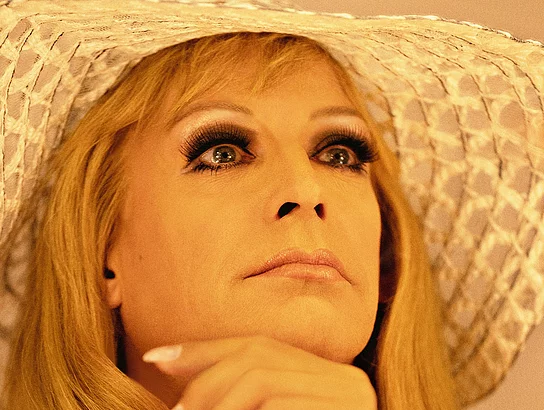 Tim Fischer in seiner Rolle als Hildegard Knef, mit Langhaarperücke und einem großen hellen Sommerhut
