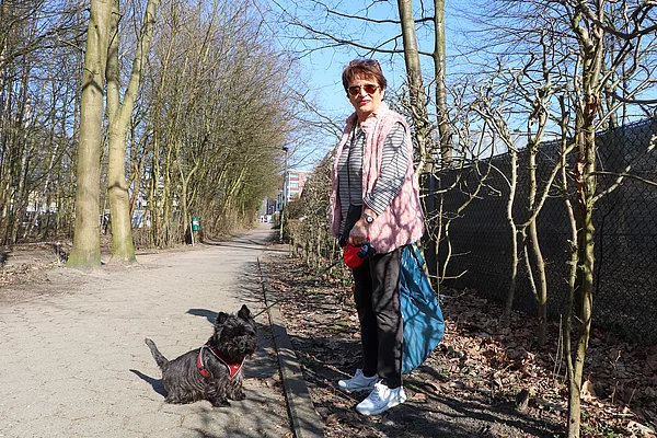 Eine Frau mit Hund sammelt Müll.