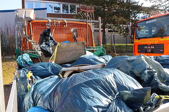 Auf der Ladefläche eines Transporters liegt viel Müll in Säcken neben einem Einkaufswagen.