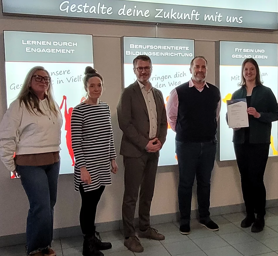 Fünf Personen stehen nebeneinander mit einer Urkunde in der Hand.