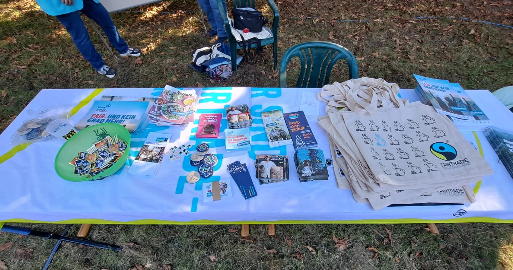 Infomaterialien wie Flyer und Beutel zum Thema Fairtade beim Nachbarschaftsfest vor dem Gutshaus liegen auf einem Tisch