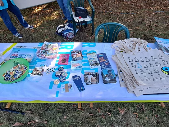 Infomaterialien wie Flyer und Beutel zum Thema Fairtade beim Nachbarschaftsfest vor dem Gutshaus liegen auf einem Tisch