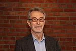 Ein Mann mit grauen Haaren, Vollbart und Brille