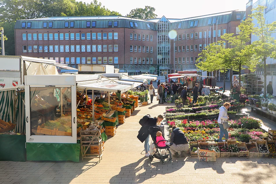 Menschen auf dem Wochenmarkt am Blumenstand und Obststand.
