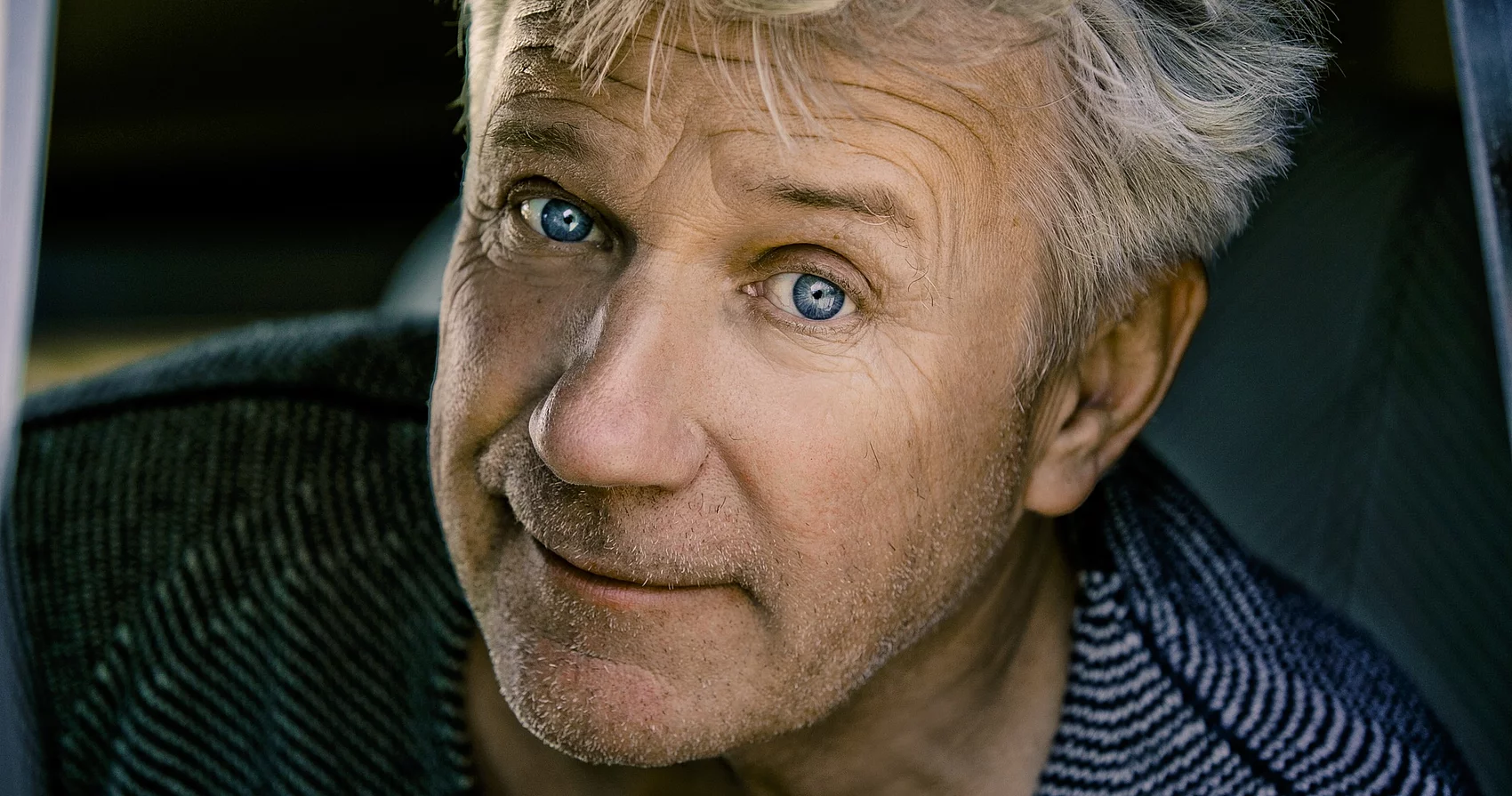 Der Schauspieler Jörg Schüttauf mit wuscheligen grauen Haaren und blauen Augen