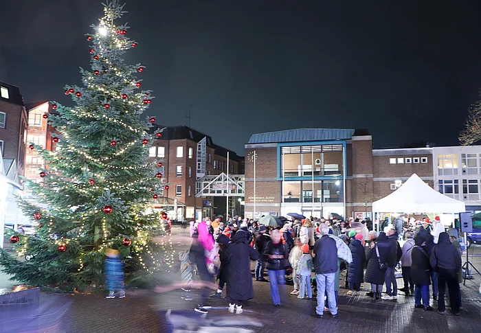 Menschen stehen am beleuchteten Weihnachtsbaum
