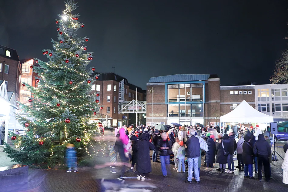 Menschen stehen am beleuchteten Weihnachtsbaum