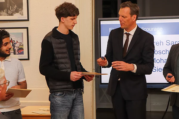 Bürgervorsteher Claus Peters ehrt einen jungen Mann.