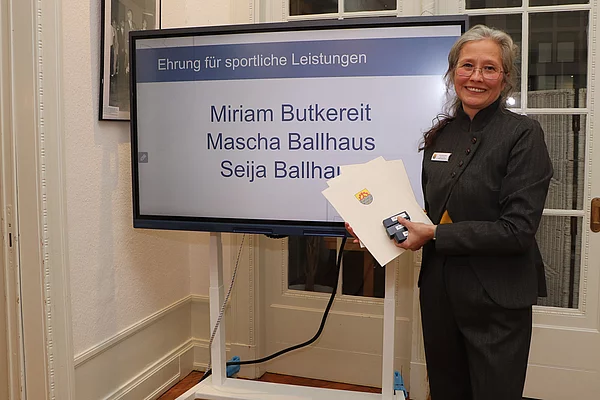 Eine Frau steht neben einem Monitor.