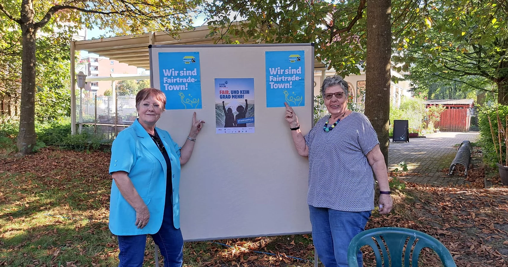Zwei Frauen stehen vor einer Pinnwand mit Plakaten zum Thema Fairtrade