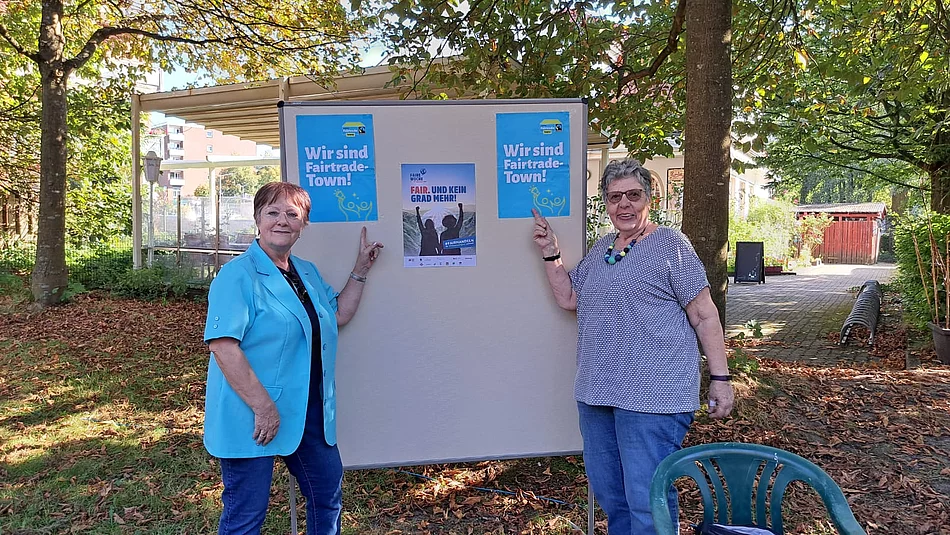 Zwei Frauen stehen vor einer Pinnwand mit Plakaten zum Thema Fairtrade