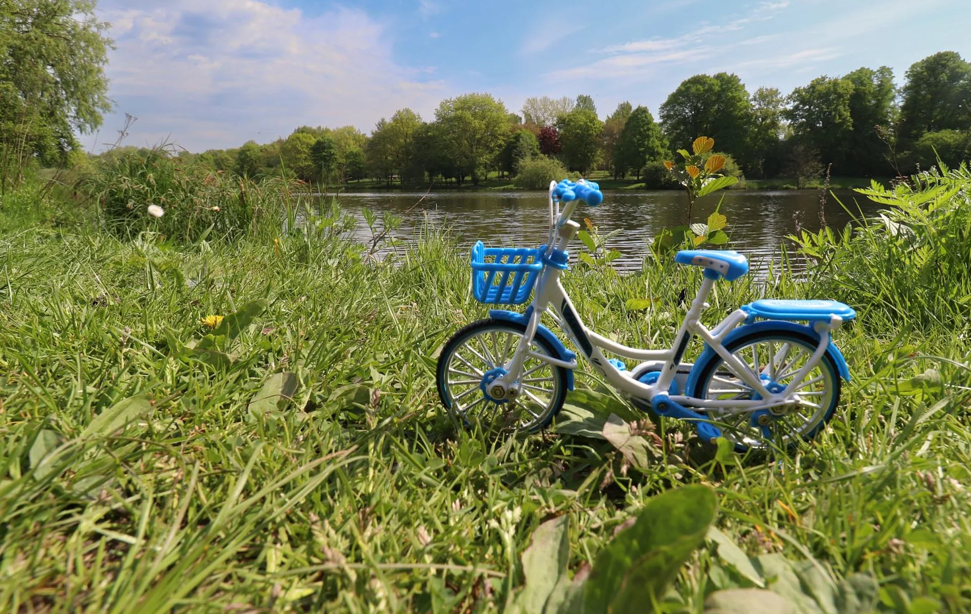 Ein blaues Miniatur-Fahrrad steht auf der Wiese am Mühlenteich.