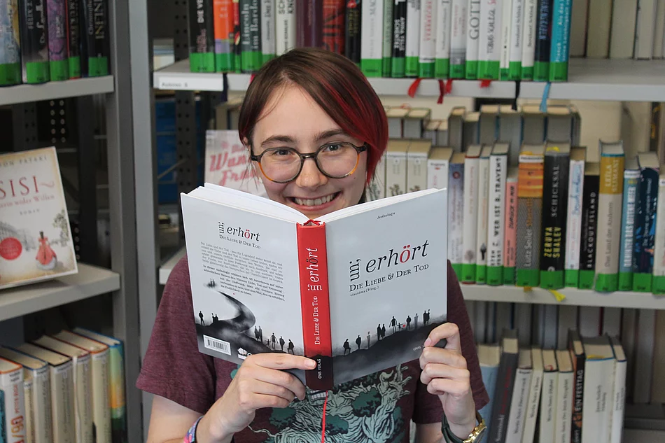 Verwaltungsmitarbeiterin Sandra Berger mit dem Buch in dem ihre Kurzgeschichte zu finden ist. Foto Stadt Glinde