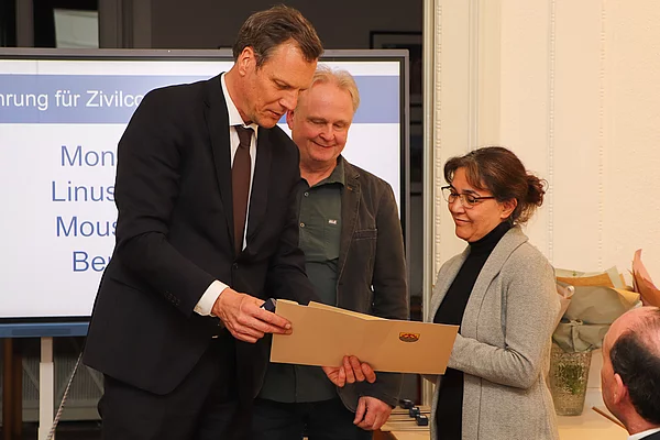 Bürgervorsteher Claus Peters übergibt eine Ehrennadel und eine Urkunde an eine Frau.