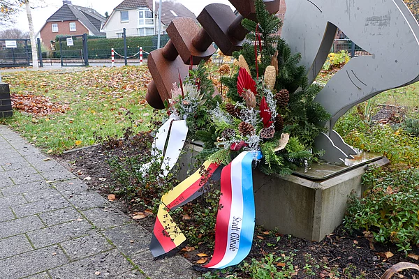 Ein Gesteck mit Schleifen steht am Mahnmal Wiesenfeld