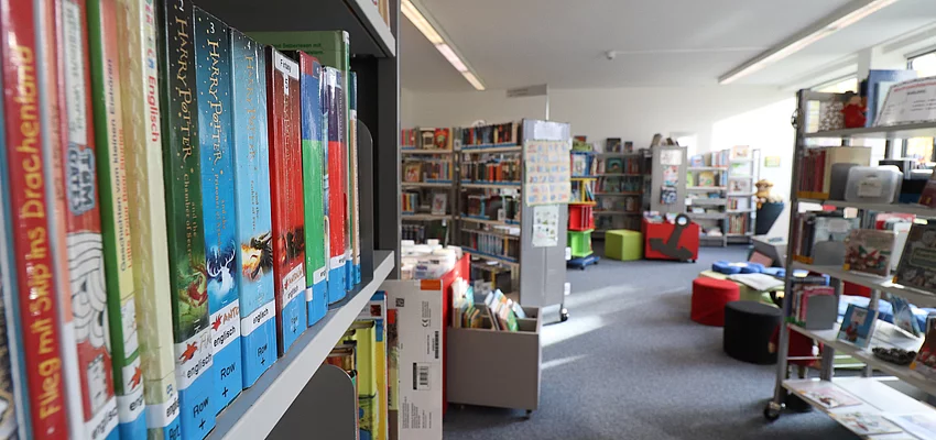 Ein Blick in die Stadtbücherei mit Regalen, Büchern und einem Lesebereich mit Kissen
