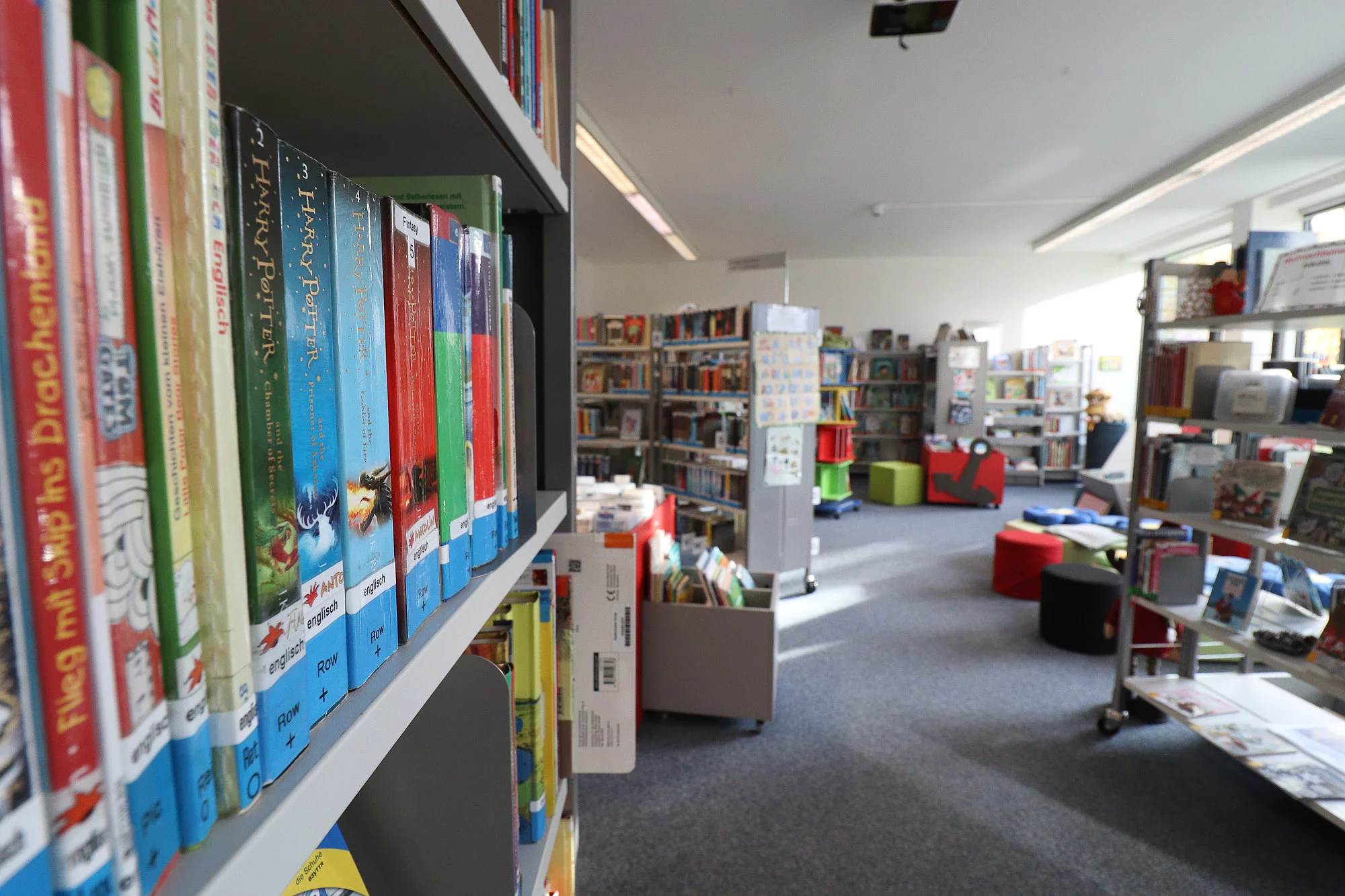 Ein Blick in die Stadtbücherei mit Regalen, Büchern und einem Lesebereich mit Kissen