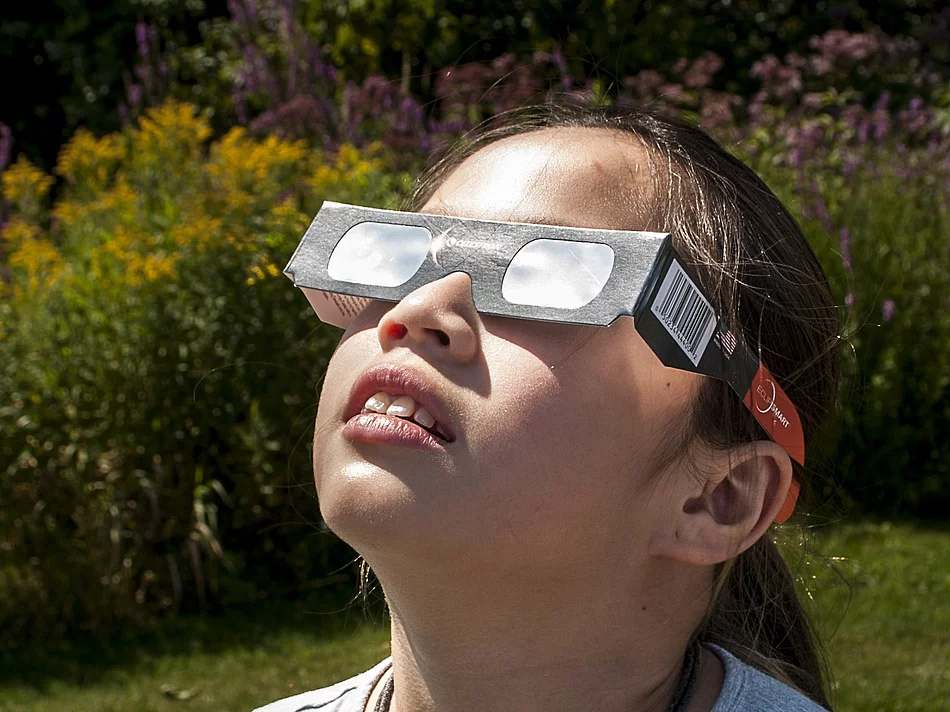 Mädchen schaut mit Schutzbrille zur Sonne Ein Mädchen mit einer Schutzbrille schaut zur Sonne.