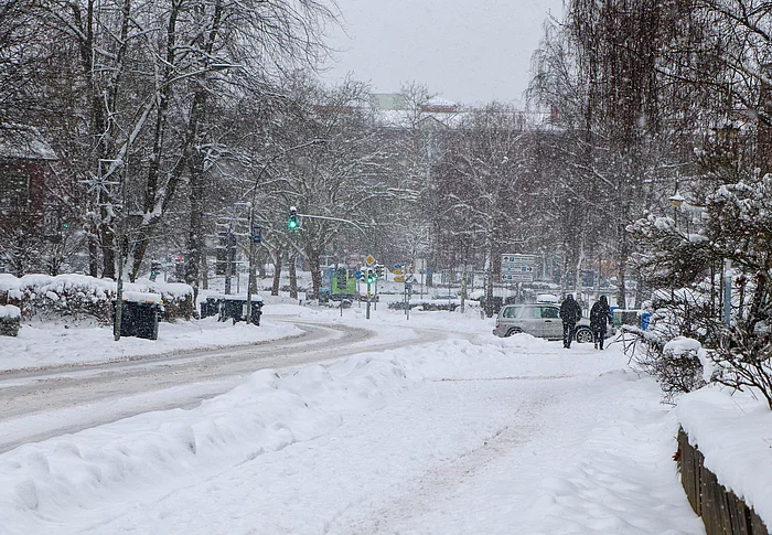 Es schneit, Menschen gehen den Oher Weg entlang und ein Auto biegt in eine Auffahrt ab.