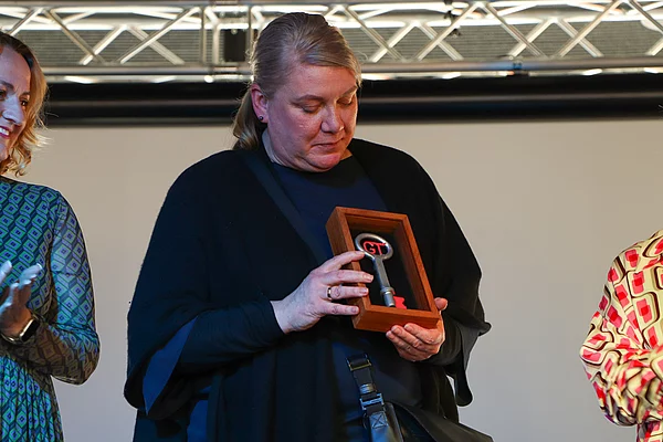 Eine Frau hält einen überdimensionalen Schlüssel vor dem Körper