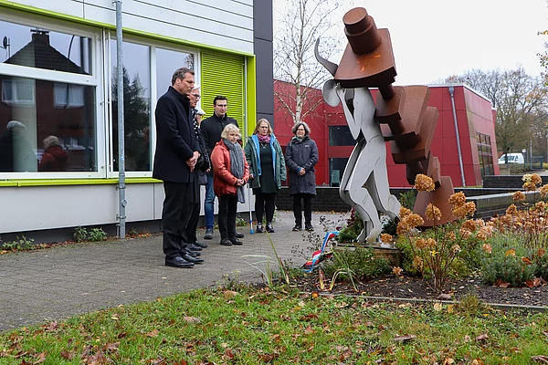 Menschen stehen am Mahnmal an der Gemeinschaftsschule Wiesenfeld.