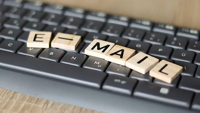 Auf einer Computertastatur liegen Holzplättchen mit dem Wort "E-Mail"