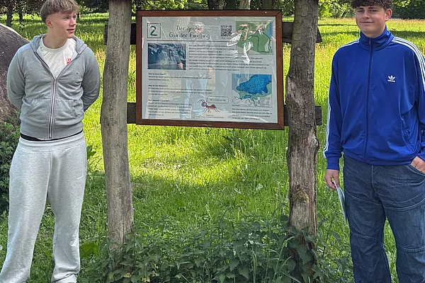 Zwei Jungs stehen an einem Schild.