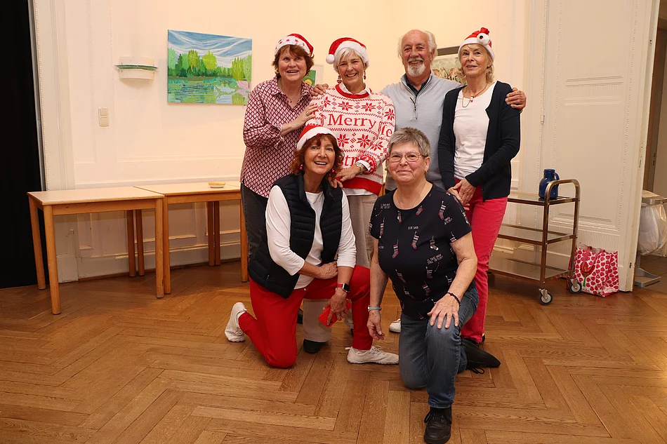 Sechs Personen haben sich zum Gruppenfoto versammelt. Sie tragen Weihnachtsmannmützen.