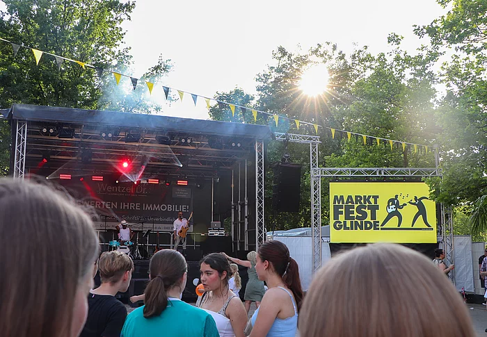 Blick zur Marktfestbühne, davor Publikum, recht eine Leinwand mit Marktfest-Logo
