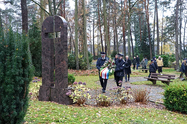 Mitglieder der Feuerwehr legen am Ehrenmal einen Gedenkkranz ab.