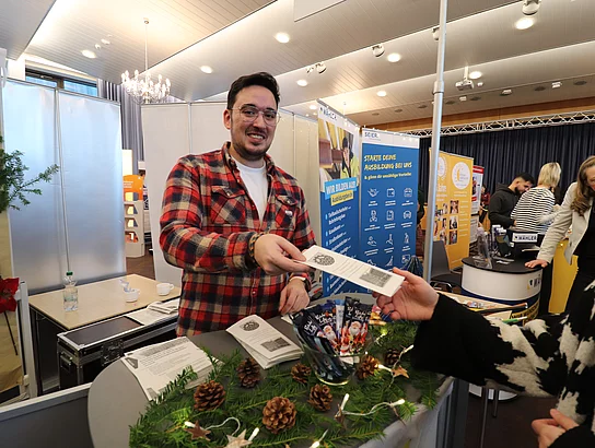 Auszubildender Timo Hiestermann übergibt einen Flyer - Ausbildungsmesse Glinde 2023