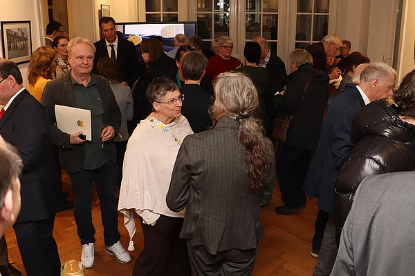 Viele Menschen sind in Gesprächen bei einem Empfang.