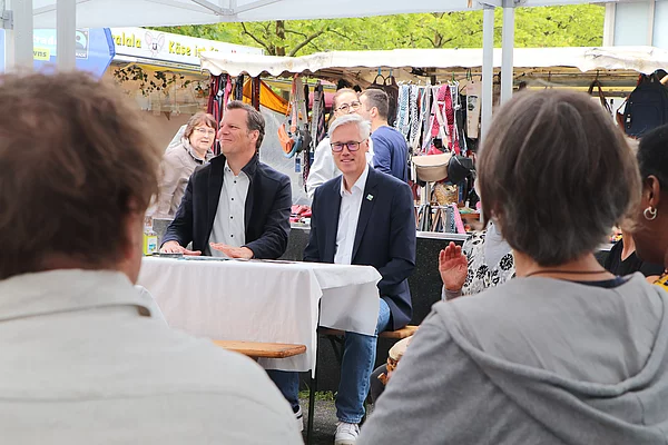 Bürgervorsteher Peters und Bürgerrmeister Zug sitzen an einem Tisch und hören den Reden zu.