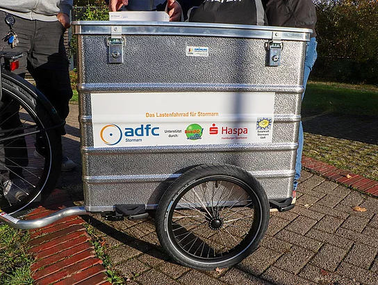 Der silberne Fahrradanhänger.