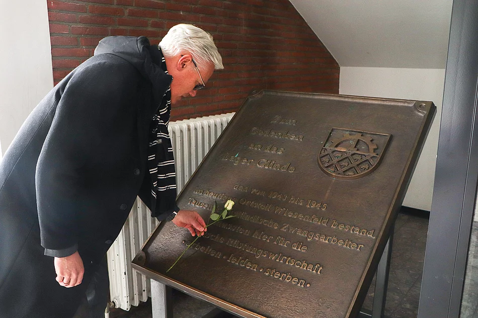 Bürgermeister Rainhard Zug legt eine weiße Rose an der Gedenktafel im Bürgerhaus ab.
