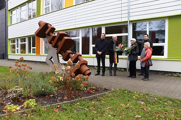 Menschen stehen am Mahnmal an der Gemeinschaftsschule Wiesenfeld.