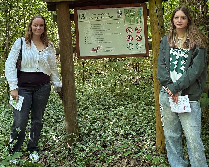 Zwei Mädchen stehen an einem Schild.