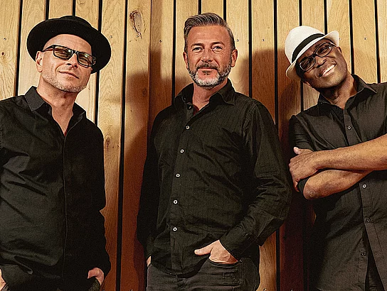 "Heet Project" bringen Soul, Funk, Pop und Rock auf die Bühne Drei Männer stehen vor einer Wand für ein Bandfoto.