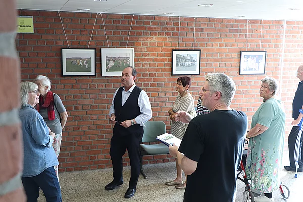 Ein Mann im schwarzen T-Shirt spricht zum Publikum, das sich Bilder anschaut.