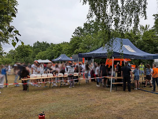Mehrere Menschen stehen an einem Zelt der Feuerwehr