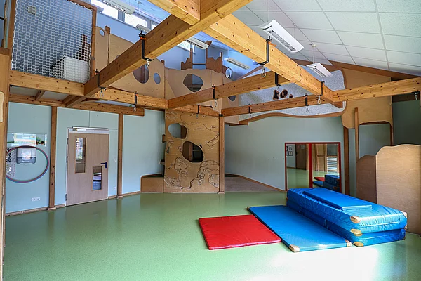 Ein Spielzimmer mit Kletterwand und Sportmatten.