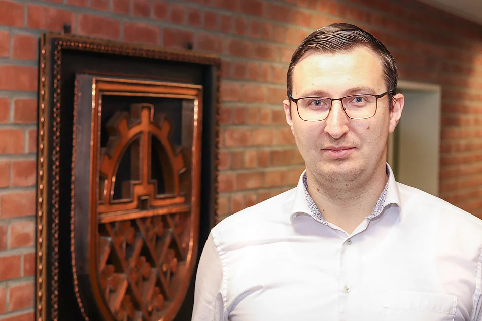 Bürgermeister Patrick Klose steht vor einem kupferfarbenen Glinder Wappen.
