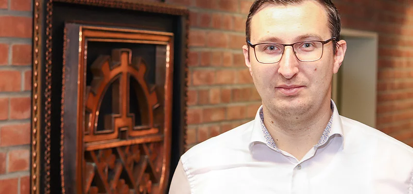 Bürgermeister Patrick Klose steht vor einem kupferfarbenen Glinder Wappen.
