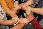 Mehrere ältere Hände fassen sich jeweils am Handgelenk und bilden einen Kreis