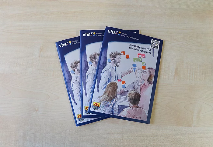 Drei Hefte mit einer Aquarellmalerei liegen auf einem Tisch.