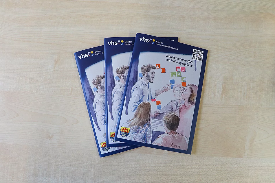 Drei Hefte mit einer Aquarellmalerei liegen auf einem Tisch.