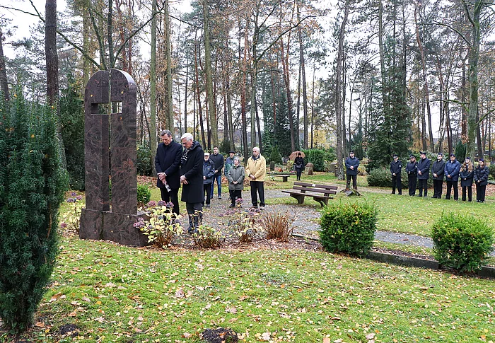 Bürgervorsteher Claus Peters, Bürgermeister Rainhard Zug und weitere Menschen gedenken am Ehrenmal