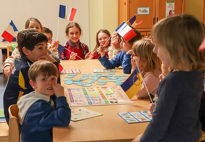 Kinder mit französischen Flaggen sitzen an einem Tisch