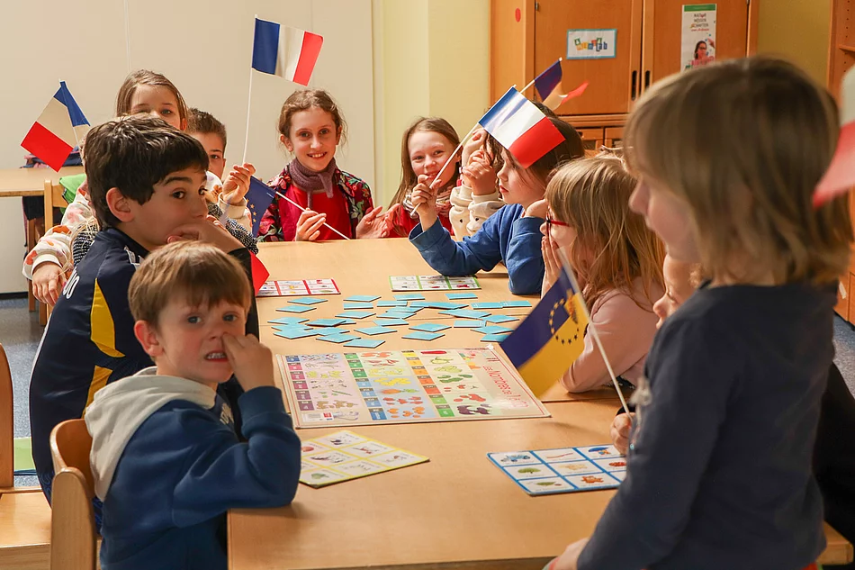 Kinder mit französischen Flaggen sitzen an einem Tisch