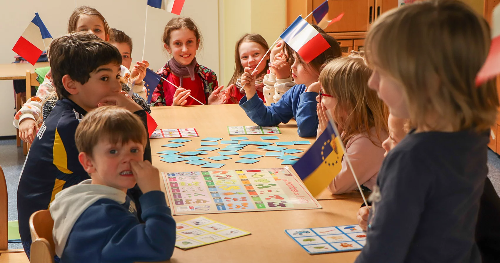 Kinder mit französischen Flaggen sitzen an einem Tisch